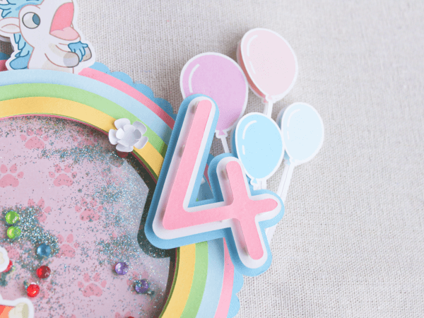 Topper para tarta personalizado, en 3D y temática Bluey. Colores Rosa, Azul y Blanco. Con motivos de los personajes, Nombre y años. Detalle Años