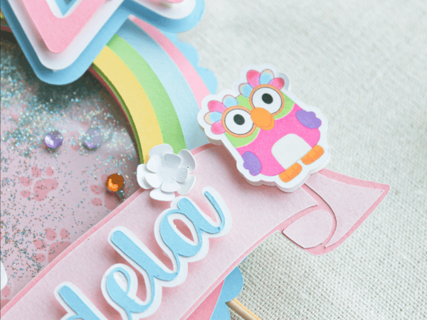 Topper para tarta personalizado, en 3D y temática Bluey. Colores Rosa, Azul y Blanco. Con motivos de los personajes, Nombre y años. Detalle Charlatán