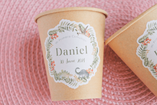 Vaso de cartón reciclable, personalizado con pegatina de evento. Diseño con estampado de hojas en tonos verde y teja y temática Dinosaurio.