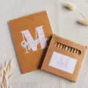 pack de lapses y libreta kraft personalizados con inicial en estampado Vichy (5 colores) y nombre. Papel liso y ambos fabricados en materiales reciclados.